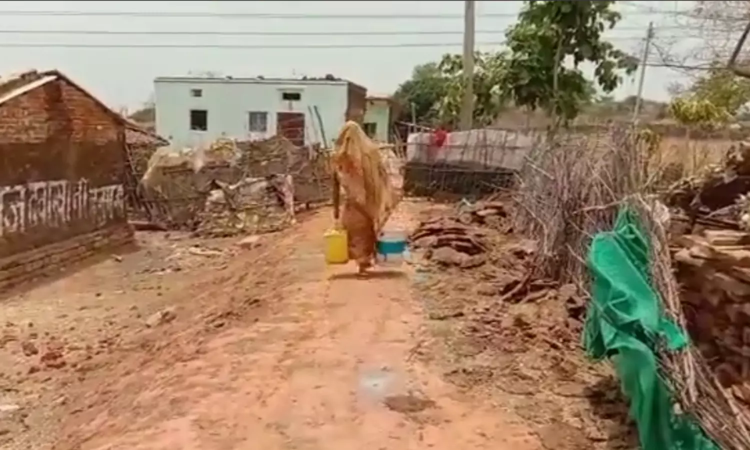 पानी की किल्लत के बीच दूर गांव से पानी ले जाती महिला