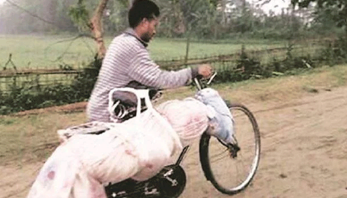 असम: CM सोनोवाल के विधानसभा क्षेत्र में साइकिल पर भाई का शव लेकर जाते शख्स की तस्वीर वायरल